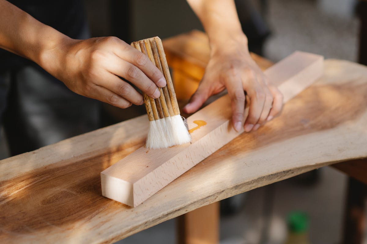 Artesano aplicando aceite en tabla de madera con brocha — tratamiento de madera