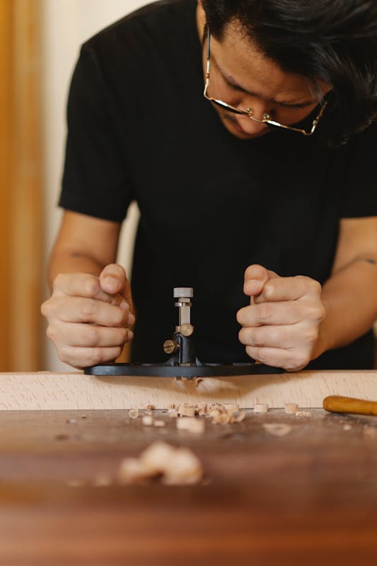 Maestro carpintero trabajando con fresadora de mano en taller artesanal