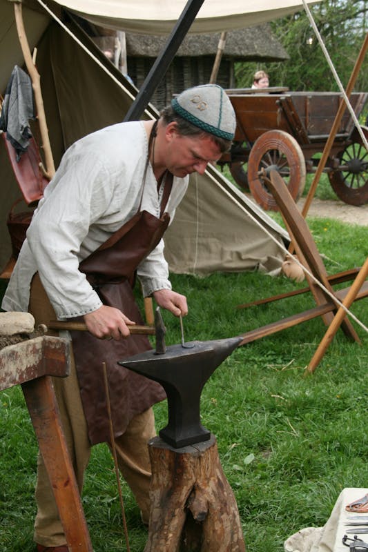 Herrero medieval en campamento histórico con yunque